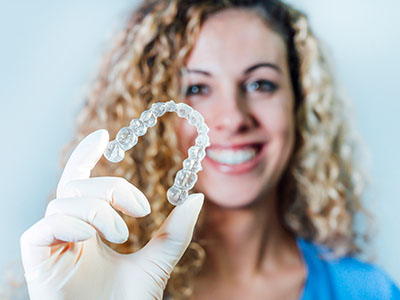 A woman holding up a transparent bracelet with a smile on her face.