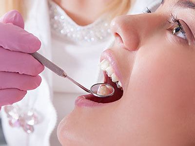 A woman receiving dental care with a dentist s hand holding a dental tool near her mouth.